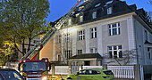 Brandbekämpfung beim Dachstuhlbrand: Gebäudeansicht mit Drehleiter 